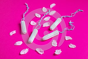 Female tampons with with cherry petals on a pink background. Hygienic white tampon for women. Cotton swab