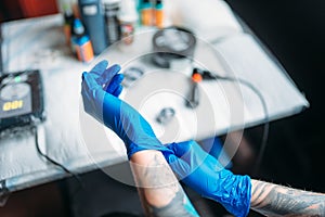 Female tattoo artist hands in blue sterile gloves