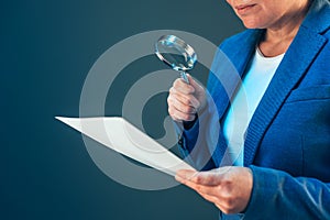 Female tax inspector looking at document with magnifying glass