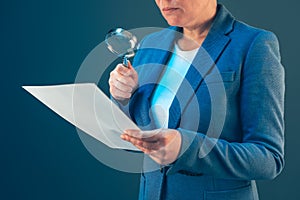 Female tax inspector looking at document with magnifying glass