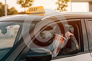 Female taxi driver with protective face mask and plastic visor