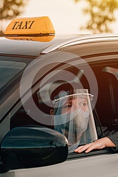 Female taxi driver with protective face mask and plastic visor