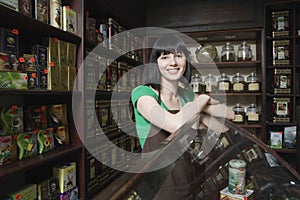 Female Tea Shop Owner Leaning On Display Cabinet