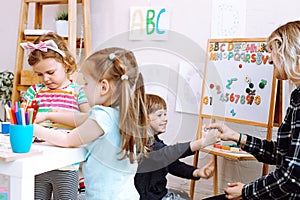 Female teacher with children have fun in development center. Paintings, art, math and English language lessons for kids