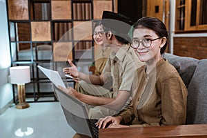 female teacher in civil servant uniform smiling looking at the camera while using a laptop computer