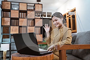 female teacher in civil servant uniform waving in front of a laptop computer