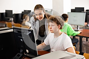 Female teacher consulting concentrated teenager in computer class