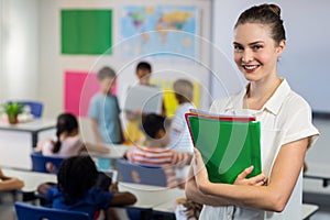 Female teacher with files standing in classroom