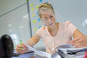 Female teacher flipping notes at desk