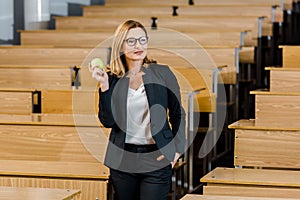 Female teacher in formal wear holding apple