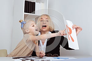 Female teacher with girl patient learning pronunciation.