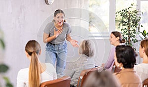 Female teacher giving lecture to group of students in classroom