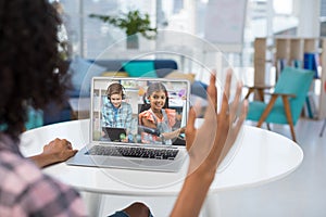 Female teacher having a video conference with male and female student on laptop at home