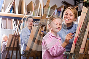 Female teacher helping girl during painting class