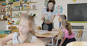 Female Teacher with kids in biology class at elementary school conducting biology or botanical scientific experiment