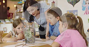 Female Teacher with kids in biology class at elementary school conducting biology or botanical scientific experiment