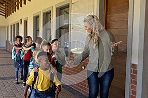 Female teacher with long blonde hair leading a group of schoolchildren at an elementary school