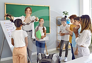 Female teacher and playful schoolchildren having fun and fooling around together during lesson.