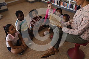 Female teacher reading a story to schoolkids