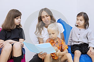 Female teacher reads a storybook to a group of kids