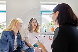 Female teacher talking to two teenage students.