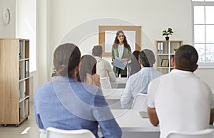 Female teacher teaches new business knowledge to adult students in training room.