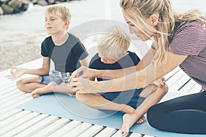 A female teacher teaches young children to do yoga in poses and properly hold the mudras on their fingers