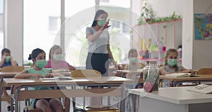 Female teacher wearing face mask at school, teaching children at school classroom. Education back to school health