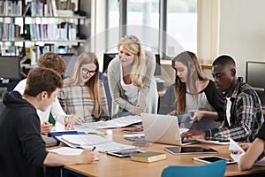 Female Teacher Working With College Students In Library