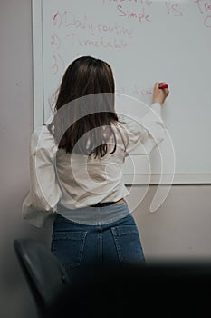 Female teacher writing on the marker board im classroom. Education concept english language lesson