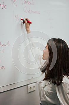 Female teacher writing on the marker board im classroom. Education concept english language lesson