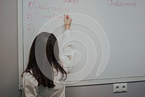 Female teacher writing on the marker board im classroom. Education concept english language lesson
