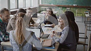 Female team leader brings documents to creative business team. Mixed race group of people meeting in modern office.