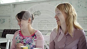 Female team during lunch in a cafe. Women in the cafe discuss the upcoming holidays. Girls drink tea from paper cups.