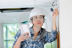 female technician adjusting cctv camera on wall