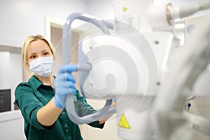 Female technician adjusts X-Ray machine. Female radiologist is going to take an Xray of patient in X-ray room of modern clinic