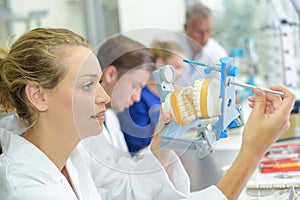 Female technician closing clamp on set dentures