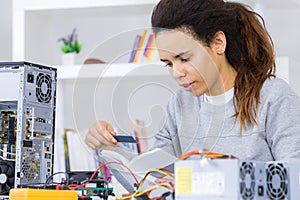 Female technician with dismantled computer and instruction book