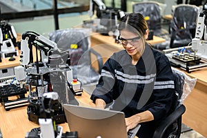 Female technician engineer using laptop checking automatic robotic machine