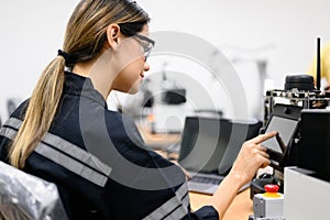 Female technician engineer using laptop checking automatic robotic machine