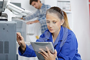 female technician fixing printer with tablet