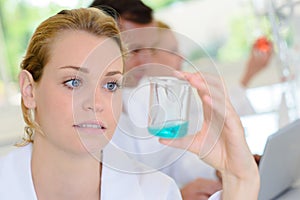 Female technician looking at liquid in glass beaker