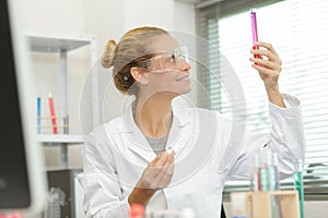 Female technician looking at liquid in glass beaker