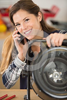 female technician making call on smartphone in workshop
