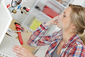 female technician servicing boiler using computer