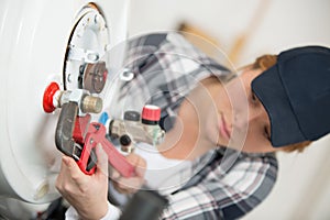female technician servicing boiler using tablet computer