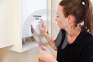 Female technician servicing boilerÃÂ using tablet computer