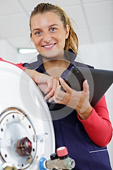 female technician servicing boiler using tablet computer