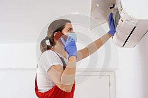Female technician using smartphone and repairing air conditioner