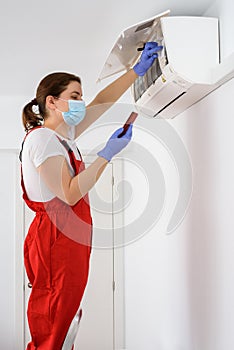 Female technician using smartphone and repairing air conditioner